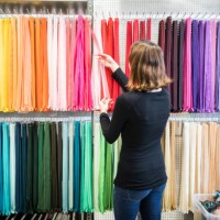 woman examining colorful zippers on rack in store - fashion stock pictures, royalty-free photos & images