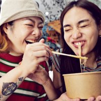 woman feeding noodles with chopsticks to friend - travel stock pictures, royalty-free photos & images