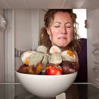 woman finds bowl of rotting fruit in the fridge. - food stockfoto's en -beelden