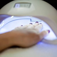 woman fliling nails with uv lamp in background. - nails art stock pictures, royalty-free photos & images