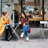 woman gesturing while talking with female friend outside coffee shop - coffee stockfoto's en -beelden