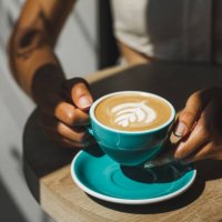 woman hands holding cup of fresh cappuccino close up. beautiful natural sun light in cafe - coffee stockfoto's en -beelden