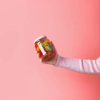 woman hands with light pink sweatshirt holding glass jar with various preserved food on pink background - food stock pictures, royalty-free photos & images