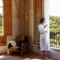 woman having coffee while standing at window - travel stockfoto's en -beelden
