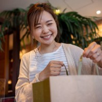 woman holding a paper bag in cafe - looking at camera - junk food stock pictures, royalty-free photos & images