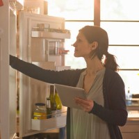 woman holding an tablet computer whilst looking in the fridge - home decoration stock pictures, royalty-free photos & images
