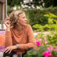 woman holding cigarette while sitting on sofa at backyard - garden decoration photos et images de collection