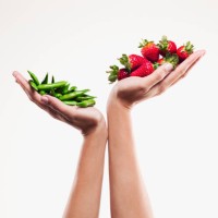 woman holding handful of strawberries over handful of pea pods - food stock pictures, royalty-free photos & images