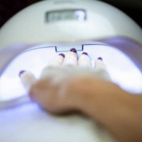 woman holding her hand under a uv lamp to set the nail polish - nails art stock pictures, royalty-free photos & images