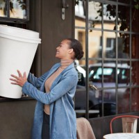 woman holding large disposable coffee cup at take away counter of cafe - junk food stock pictures, royalty-free photos & images