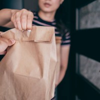 woman holding paper bag with take out food, home delivery, food order - junk food stock pictures, royalty-free photos & images