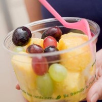 woman holding plastic tub of fruit salad with fork - junk food stock pictures, royalty-free photos & images