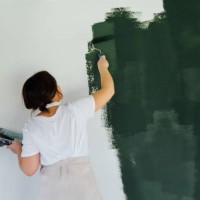 woman in head phones painting white wall in green color - home decoration stock pictures, royalty-free photos & images