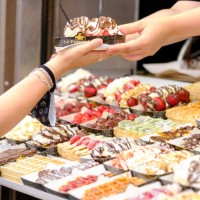 Woman is buying a waffle in a shop on July 29, 2021 in Brussels, Belgium. A waffle is a pastry made with a light dough baked in a waffle iron...