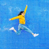 woman jumping in front of a blue background - fashion stock-fotos und bilder