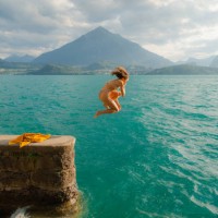 woman jumping into the lake in swiss alps - travel stock-fotos und bilder