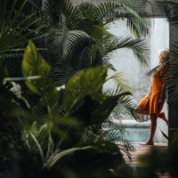 woman leaning on a gray concrete stone wall surrounded by green tropical palm leaves, by the pool. - fashion stock pictures, royalty-free photos & images