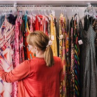 woman looking at dress hanging on rack while standing at store - fashion stock pictures, royalty-free photos & images