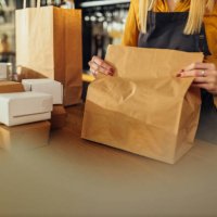 woman packing food in paper bags - junk food stock pictures, royalty-free photos & images