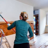 woman painting the kitchen wall using paint roller - home decoration stockfoto's en -beelden