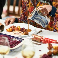 woman pouring gravy onto roast dinner with christmas crackers on table - food stock pictures, royalty-free photos & images