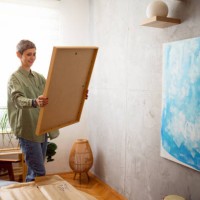 woman preparing a new painting to hang it on the wall - home decoration stock pictures, royalty-free photos & images