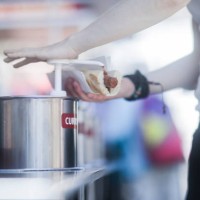 woman putting curry sauce on a hotdog - junk food stock-fotos und bilder