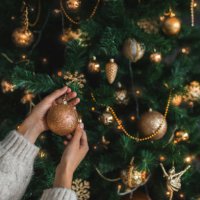 woman putting on christmas tree golden ornaments. - home decoration stock pictures, royalty-free photos & images