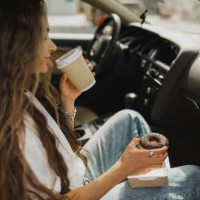 woman relaxing in car and enjoying coffee with donut. fast food in road trip. - junk food stock pictures, royalty-free photos & images