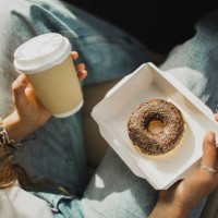 woman relaxing in car and holding cup of coffee and paper box with chocolate donut - junk food stock pictures, royalty-free photos & images