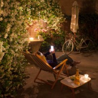 woman relaxing on deck chair in backyard at night, holding mobile phone - garden decoration photos et images de collection