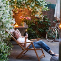 woman relaxing on deck chair in backyard, reading on mobile phone - garden decoration photos et images de collection