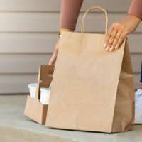 woman retrieves takeout food order front her front porch after it is delivered - junk food stock pictures, royalty-free photos & images