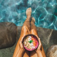 woman's hand holding fresh fruit smoothie bowl on background of turquoise water in swimming pool - food stock pictures, royalty-free photos & images