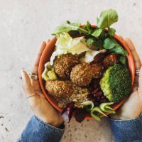 woman's hands holding bowl with falafel, broccoli, greens, cherry tomatoes, red beans, beetroot and quinoa - junk food stock pictures, royalty-free photos & images