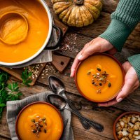 woman serving two bowls of pumpkin soup for thanksgiving meal - food stock pictures, royalty-free photos & images