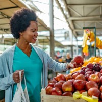 woman shopping for fresh organic fruits in farmers market with a eco bag. - food stockfoto's en -beelden