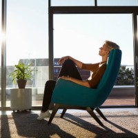 woman sitting in armchair in sunlight with closed eyes - home decoration stock pictures, royalty-free photos & images