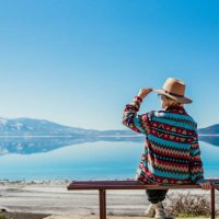 woman sitting near beautiful blue lake with white sand beach and enjoying its stunning view. salda lake, turkey - travel stockfoto's en -beelden