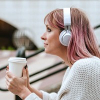 woman sitting on stairs with coffee and headphones - junk food stock pictures, royalty-free photos & images