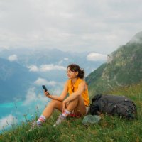 woman sitting on the meadow in swiss alps using smartphone during the hike - travel stock pictures, royalty-free photos & images