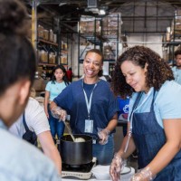 woman smiles at friend while preparing food for hungry - food stock pictures, royalty-free photos & images