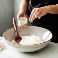 woman sprinkling salt in flour before mixing - food stock pictures, royalty-free photos & images