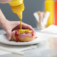 woman squirting donut with ketchup and mustard - food stock pictures, royalty-free photos & images