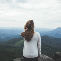 woman stares out at a beautiful mountain scene - fashion stock-fotos und bilder