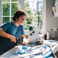 woman tailoring with twist: mature female tailor cuts fabric, creating a new dress design in bright workshop studio - home decoration stock pictures, royalty-free photos & images