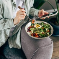 woman taking photo of fresh, spring, vegetable salad with smartphone. using phone while eating lunch. lifestyle trend - posting and sharing food pictures (images) on social media. - junk food stock pictures, royalty-free phot
