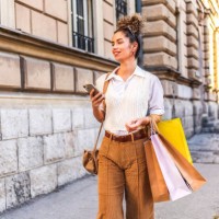 woman using a mobile phone and carrying shopping bags - fashion stock pictures, royalty-free photos & images