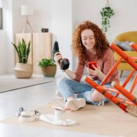 woman using a mobile phone while renovating and repairing an old chair. - home decoration stock pictures, royalty-free photos & images