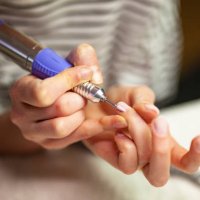 woman using electric nail file to clean cuticles. - nails art stock pictures, royalty-free photos & images
